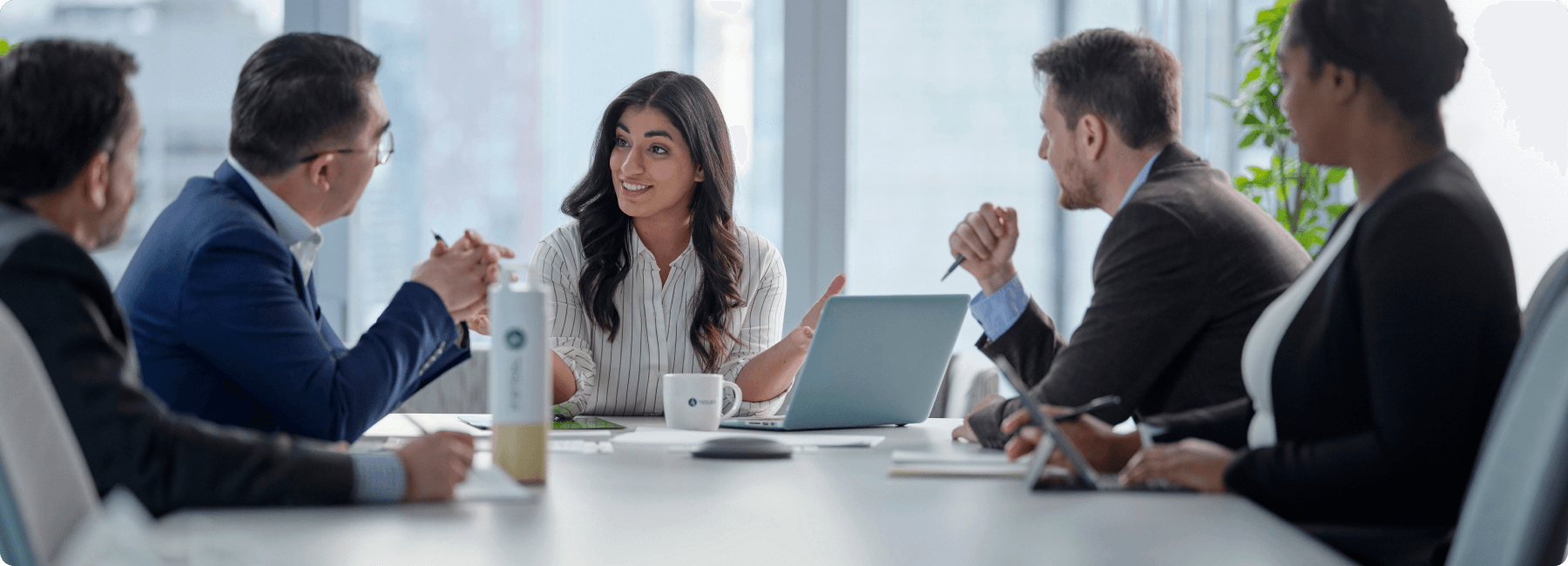 five colleagues in meeting at shared desk