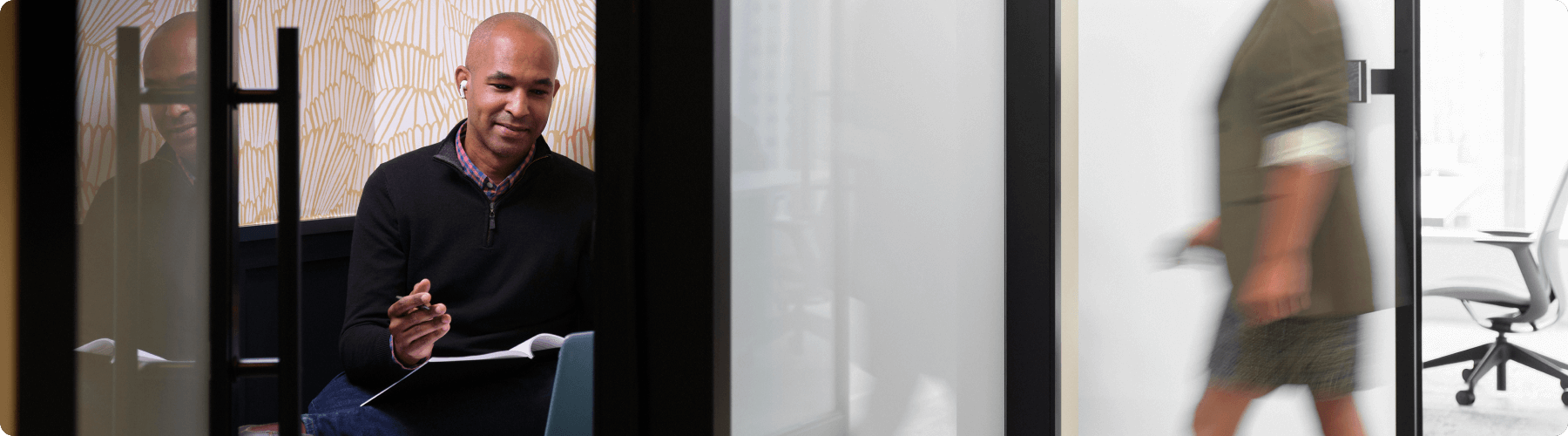 Man in small meeting booth writing notes