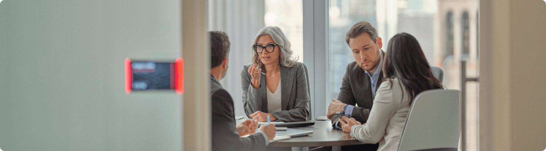 four colleagues sitting at shared desk in a meeting